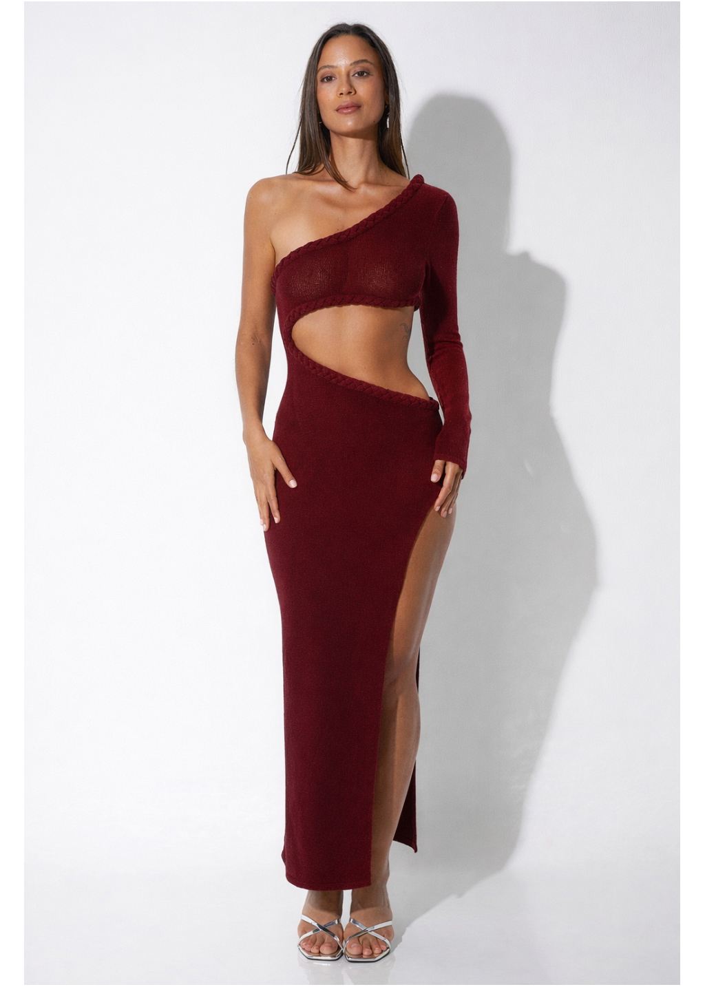 Woman wearing a burgundy one-shoulder dress with cut-out design on a white background
